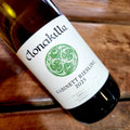 A bottle of Clonakilla Kabinett Riesling 2025 vintage, angled diagonally on a rustic wooden surface.