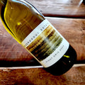 A bottle of Mooroduc Estate Pinot Gris 2024 white wine resting on a rustic wooden plank surface.
